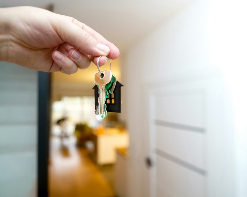 Hand holding house keys at a new home entrance
